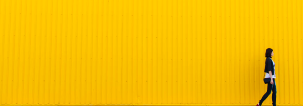 Mujer caminando sobre fondo amarillo